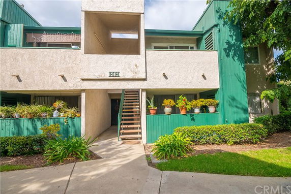 Front view of a two-story apartment building with a staircase and green accents.