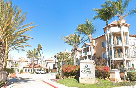 Front view of a multi-story residential complex with balconies and palm trees.