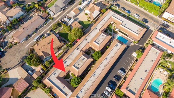 Aerial view of a complex with adjacent parking area and nearby residential buildings.