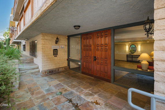 Entrance view of a condominium building with a wooden door and glass window.
