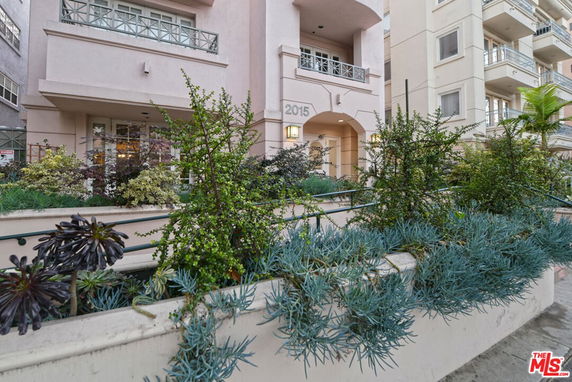 Front view of a multi-story building with balconies and a landscaped entrance.