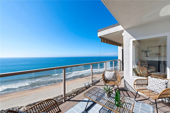 Balcony view overlooking the ocean with wicker chairs and table.