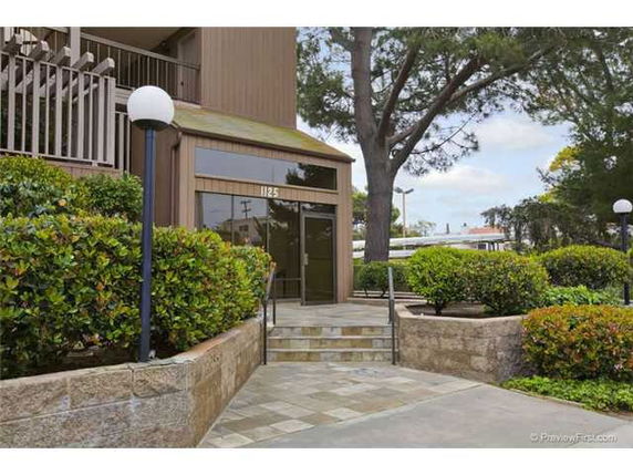 Front view of a building entrance with glass doors and surrounding greenery.
