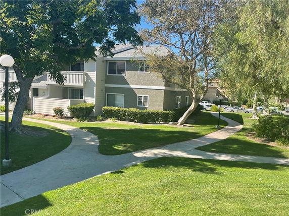 Front view of a two-story apartment building with a pathway and trees.