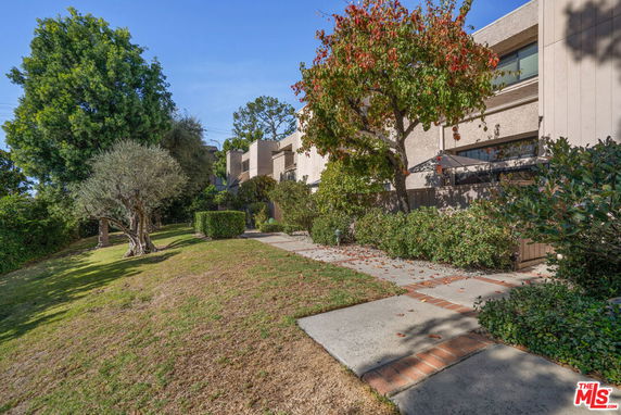 Front view of a multi-story building with trees and shrubs