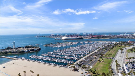 Panoramic view of a marina and harbor with numerous boats and ships, surrounded by water and coastline.