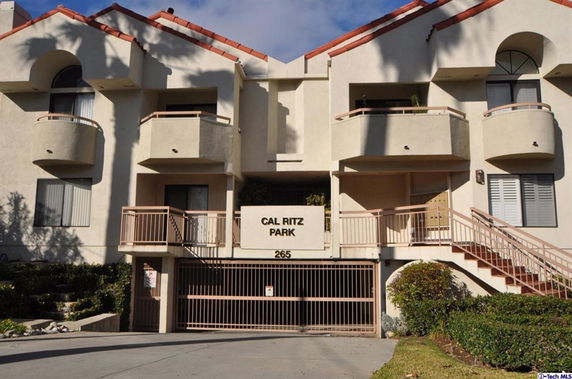 Front view of a multi-story residential building with balconies and a gated entrance.