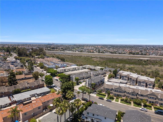 Aerial view of a residential area with houses and roads, and a distant view of a cityscape.