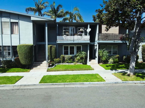 Front view of a two-story apartment building with balconies and staircases.