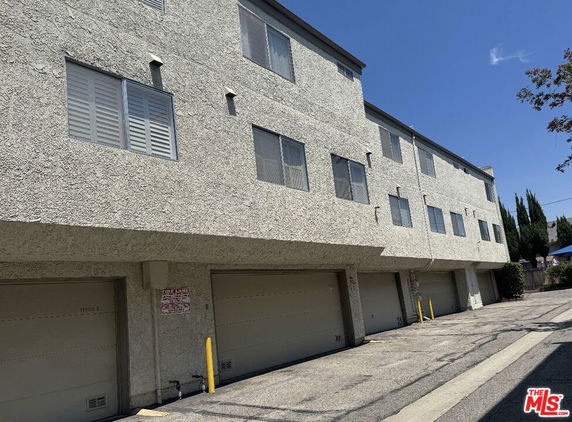 Front view of a multi-story building with a row of garages.