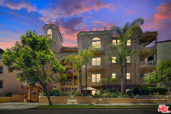 Front view of a multi-story building with balconies and decorative arches.