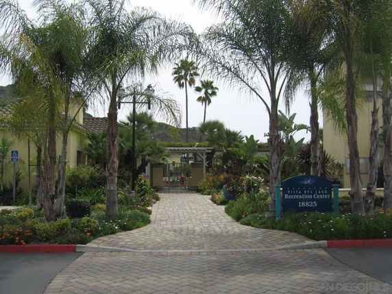 Front view of a recreation center with palm trees and a landscaped path leading to the entrance.