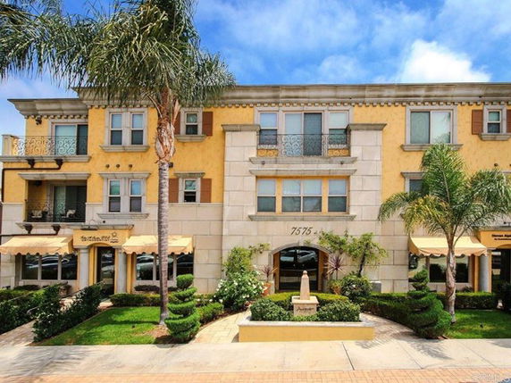 Front view of a three-story building with decorative columns and balconies.