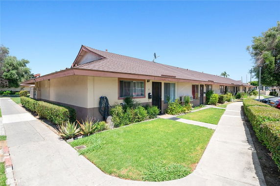 Front view of a single-story house with multiple entrances and a sidewalk.