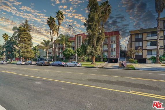 Front view of multi-story apartment buildings with balconies and trees.