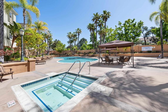 Outdoor swimming pool area with palm trees and seating.