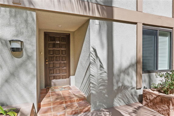Front view of a building entrance with a brown door and light fixture.