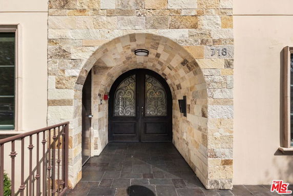 Front view of a building entrance with stone arch and double doors