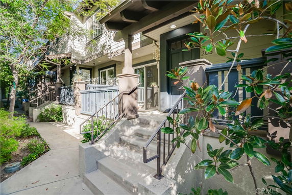Front view of a multi-story house with a porch and stairs leading up to the entrance.