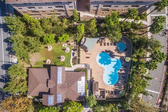 Aerial view of a swimming pool area surrounded by trees and buildings.