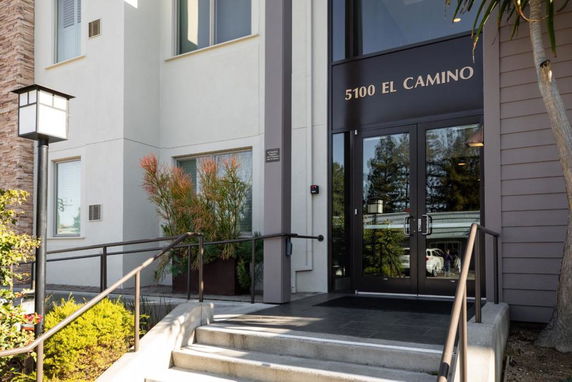 Front view of a building entrance with steps and glass doors.