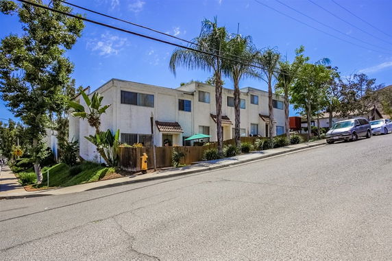 Front view of a multi-story residential building with palm trees.