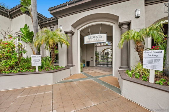 Front view of a condominium entrance with signage and planters.