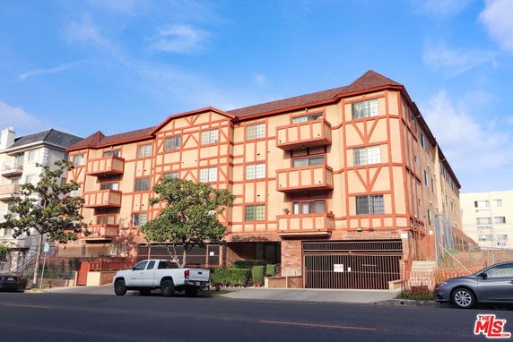 Front view of a multi-story building with a distinct red and beige facade and multiple balconies.