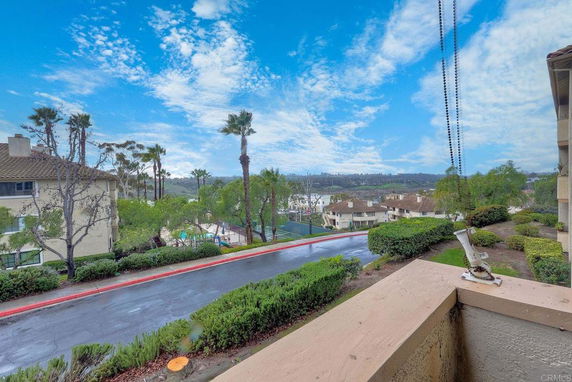 View of residential buildings and surrounding greenery with a clear sky in the background.
