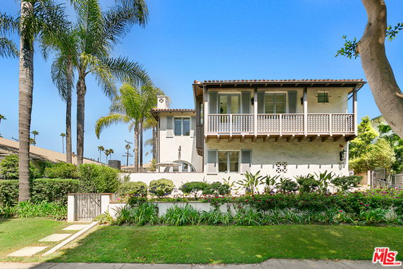 Front view of a two-story house with balconies and landscaped surroundings.
