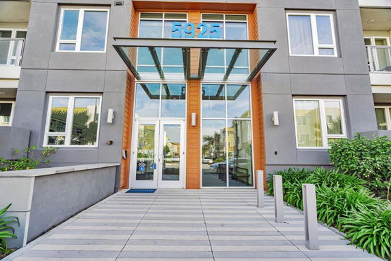 Front view of a modern multi-story building with large windows and a glass entrance canopy.