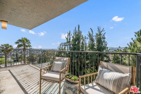 Outdoor balcony with chairs overlooking a scenic view with trees and a distant horizon.