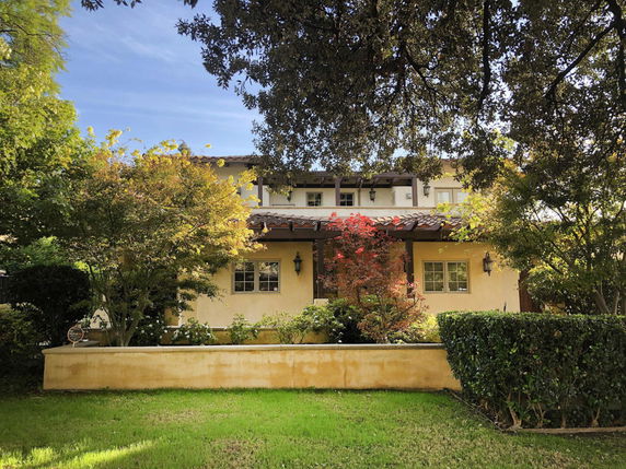 Front view of a two-story house with a porch and a tiled roof.