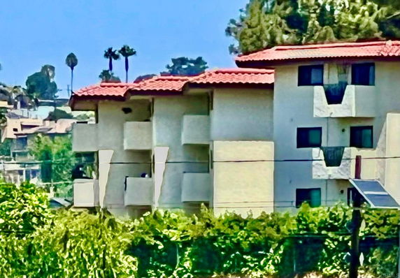 Front view of a multi-story apartment building with balconies and red roof.