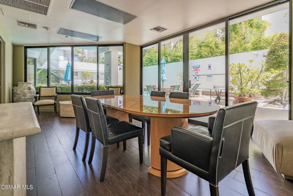 Indoor clubhouse area with a large table, chairs, and glass windows overlooking the outside.