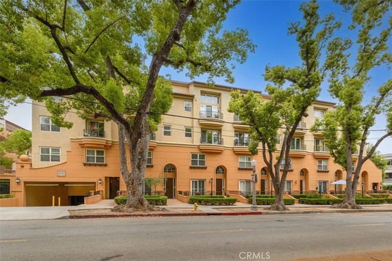 Front view of a multi-story residential building with trees lining the street.