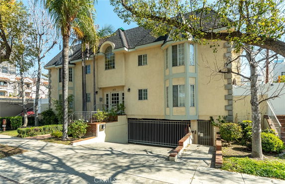 Front view of a multi-story house with a gated entrance and a landscaped front yard.