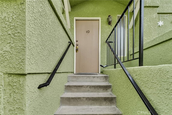 Entrance with stairs leading to a doorway in a green stucco building.