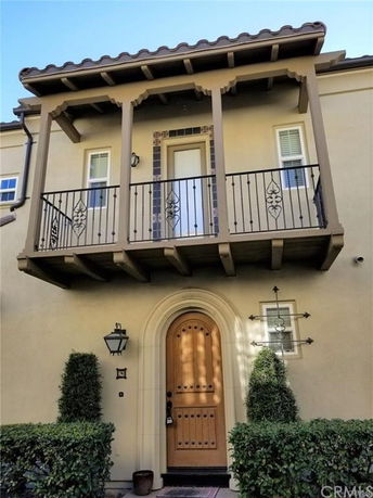 Front view of a house with a balcony and decorative wrought iron railing.