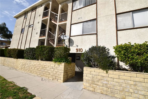 Front view of a multi-story apartment building with balconies and a satellite dish.