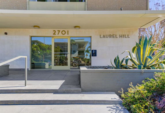 Entrance view of a building with glass doors and a vertical sign that reads 'LAUREL HILL'.