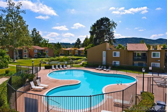 Outdoor swimming pool area surrounded by residential buildings and greenery.