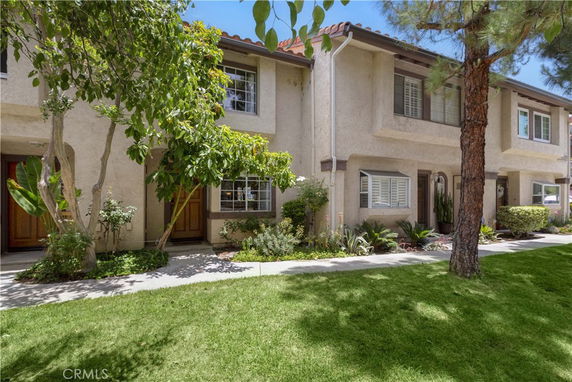 Front view of a two-story townhouse with a garden.