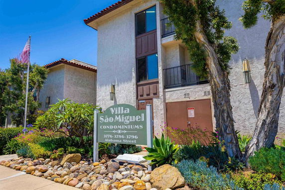 Front view of condominium building with balconies and entrance signage.