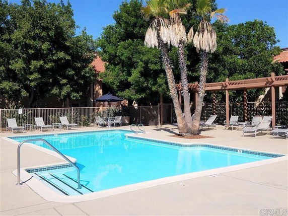 Outdoor swimming pool area with lounge chairs and trees around.