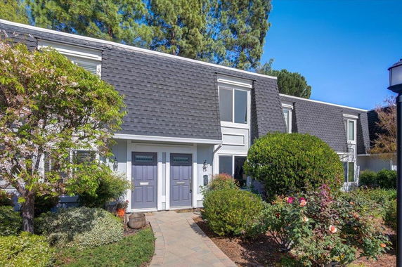 Front view of a two-story house with dark grey roofing and double front doors.