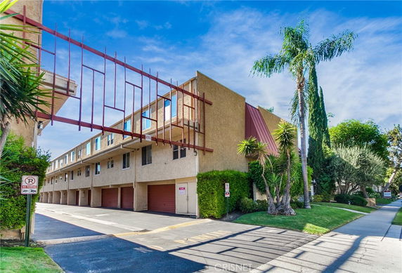 Side view of a multi-story building with garages on the ground floor.