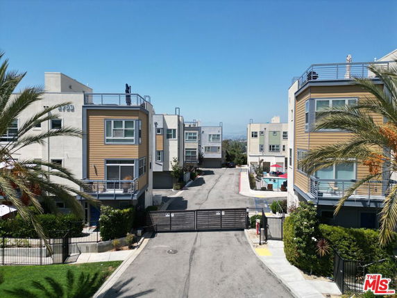 Front view of a modern multi-story apartment complex with gated entry.