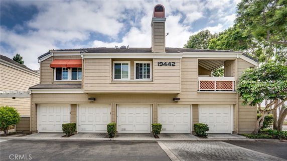 Front view of a two-story house with a triple garage and a chimney.