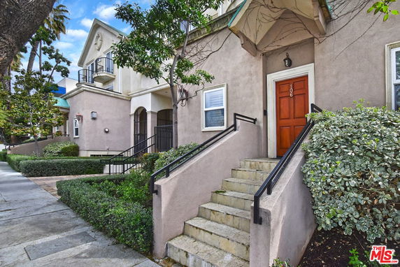 Front view of a residential building with stairs leading to a red door.